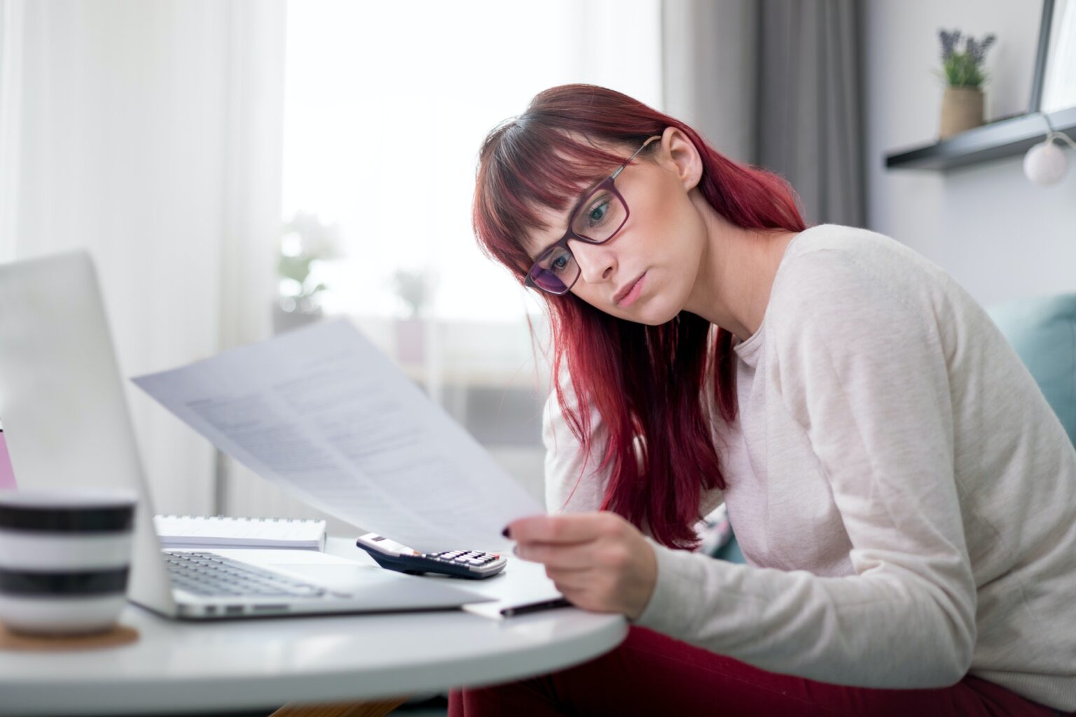 worried-woman-at-home-checking-financial-documents-using-calculator-and-laptop-1536x1024-1